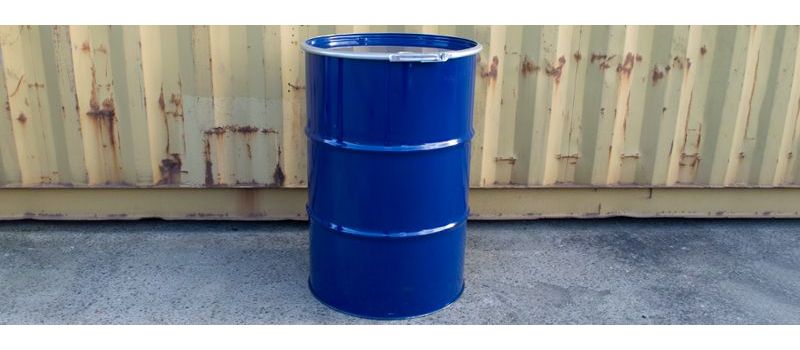 blue steel tight head barrel stood against a shipping container