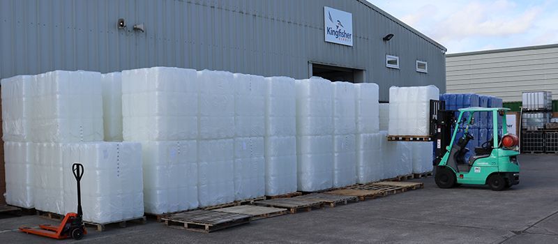 multiple pallets of jerry cans being stacked outside by forklift