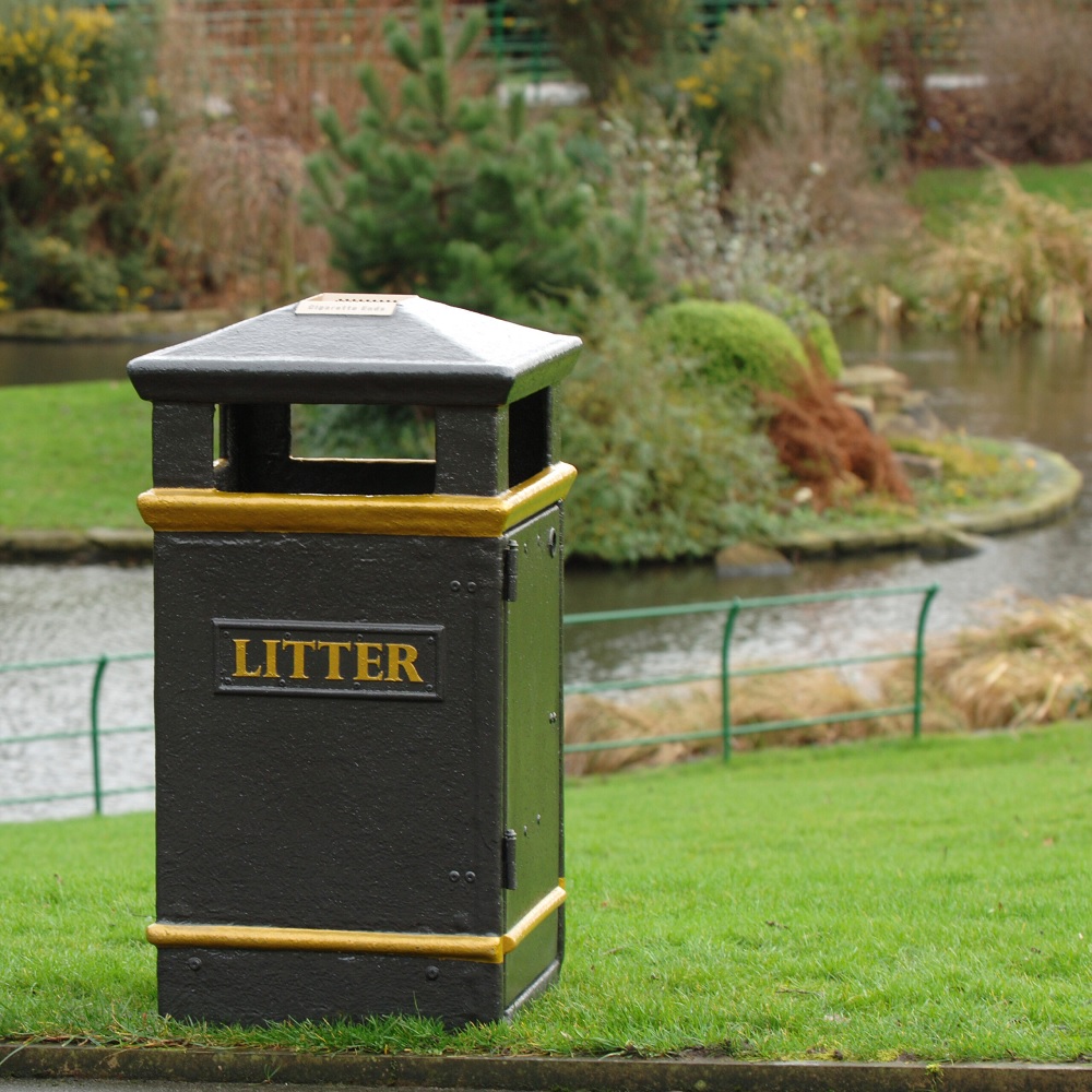 Closed top black GFC litter bin with ash tray on top in an outdoor setting.